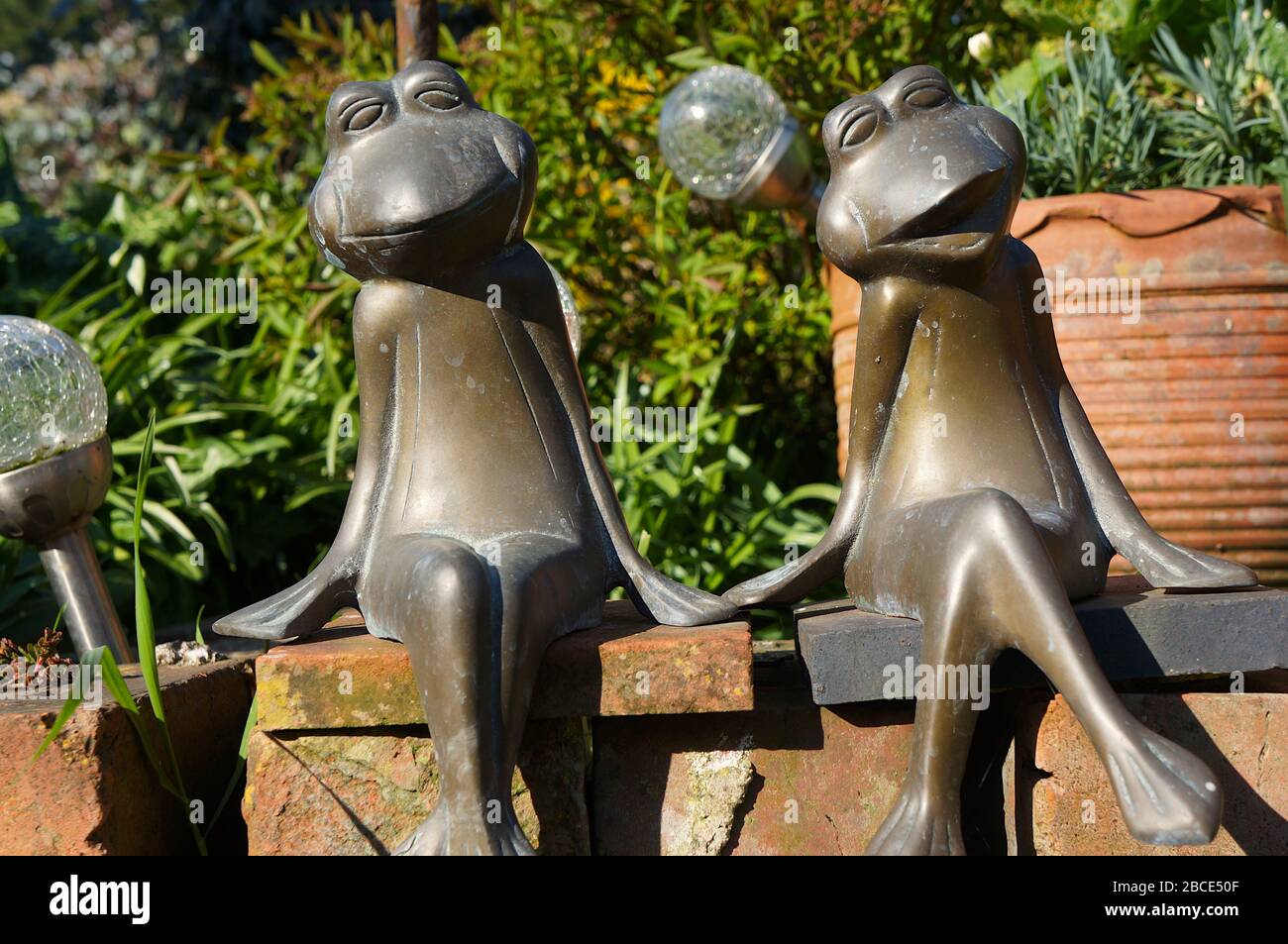 frog garden ornaments sitting on edge of the flower bed with soft focus background Stock Photo