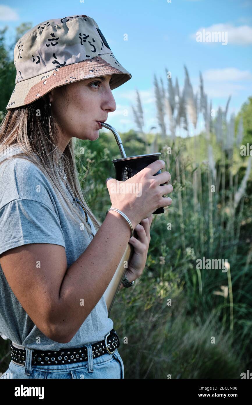 a beautiful girl model drinking yerba mate hot infusion beside the river in Bel Ville City, Cordoba, Argentina Stock Photo