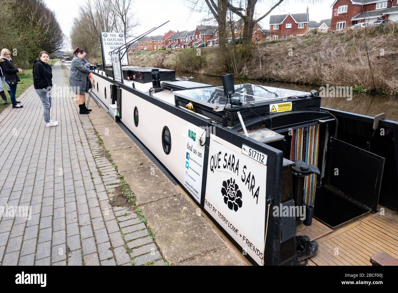 People buying food (Staffordshire oatcakes) from a narrowboat ()Que Sara Sara, the B'oatcake boat) on a canal, Stoke-on-Trent, Staffordshire, UK Stock Photo