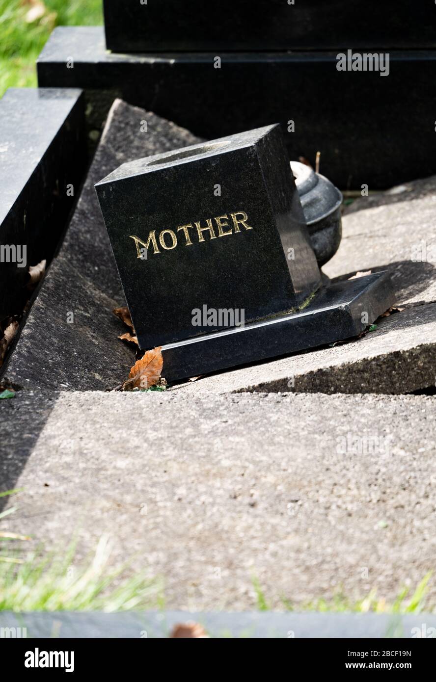A damaged modern grave with the inscription 'Mother' in a graveyard, UK Stock Photo