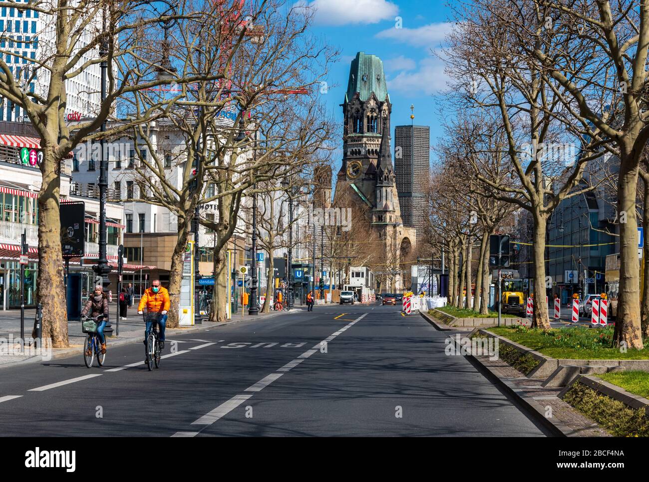 Cyclist with face mask riding down Kurfurstendamm Boulevard in central Berlin deserted due  the corona pandemic lockdown Stock Photo