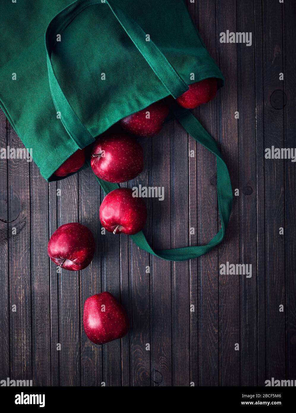Online shopping delivery. Eco friendly bag with red apples on dark wooden background Stock Photo