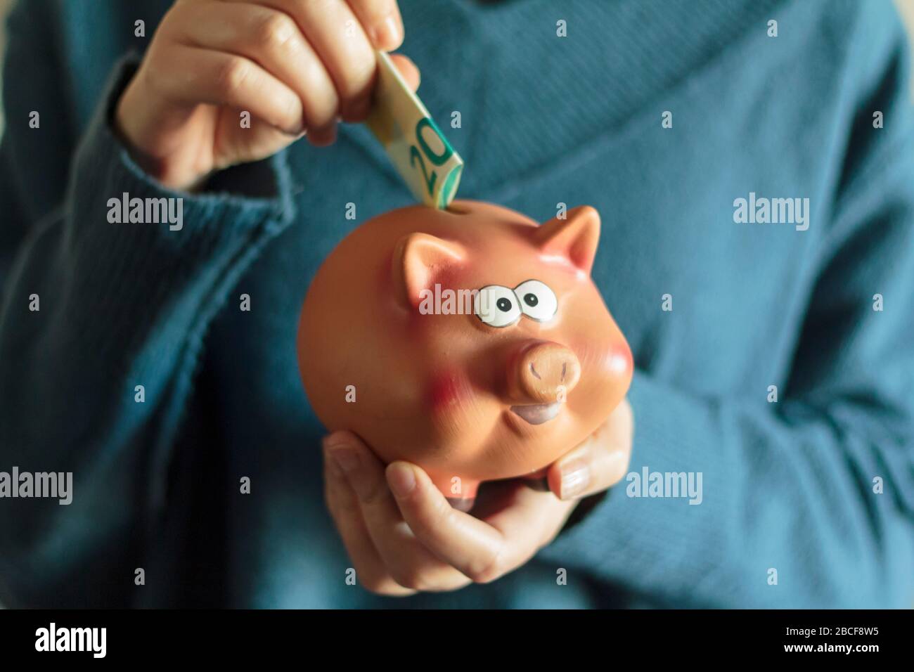 Woman put banknote on piggy bank Stock Photo - Alamy
