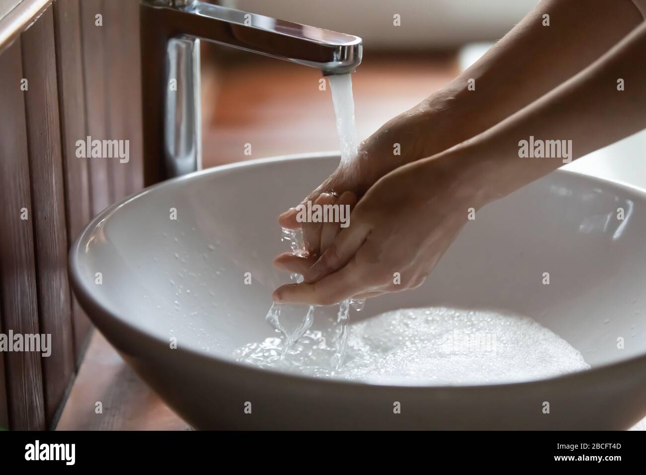 Young woman rinsing off bubble antibacterial soap from hands Stock