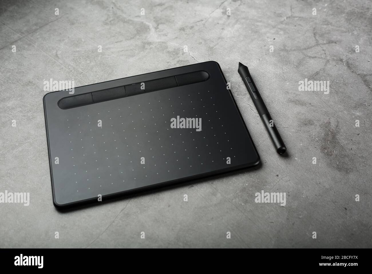 Graphic tablet with a stylus on a dark textural background, top view. Gadget for working as a designer, artist and photographer. Stock Photo