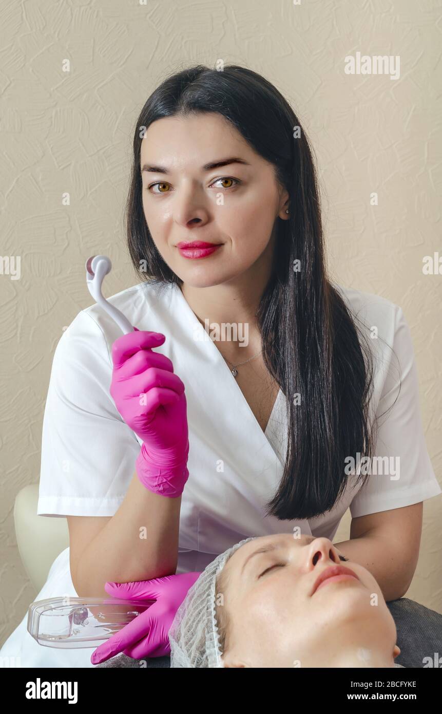 Cosmetologist shows mesoscooter. Carrying out anti-aging treatments in spa Stock Photo