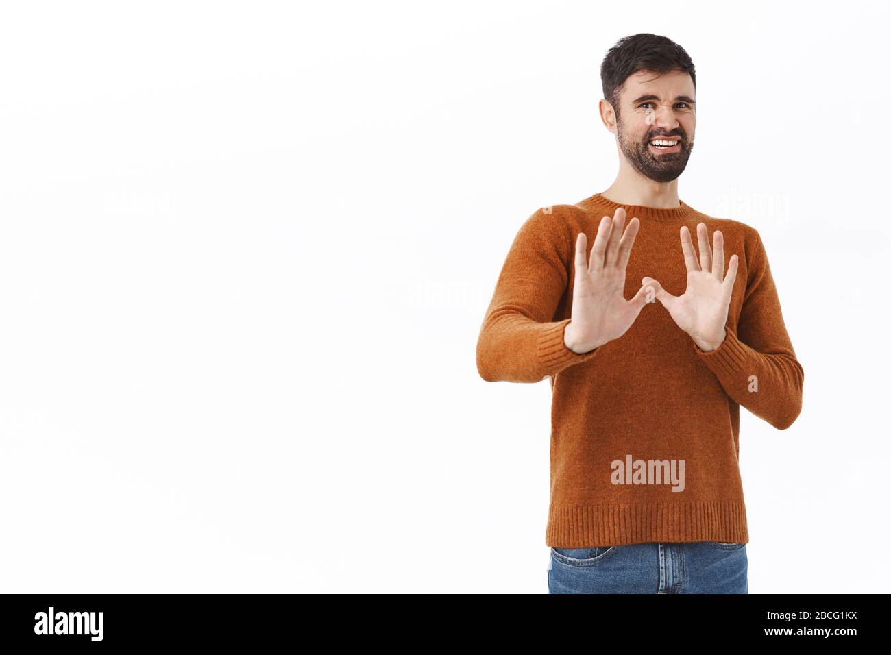 No thank you I pass. Portrait of disgusted young grimacing bearded man asking stay away, keep distance, shaking hands in defense and refusal, step Stock Photo