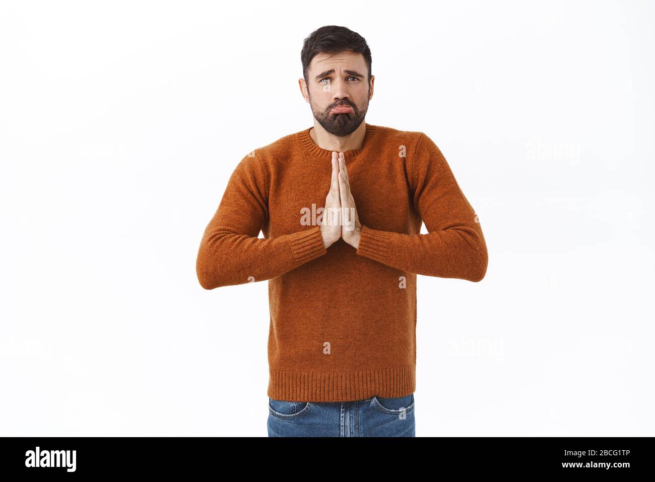 Portrait of gloomy whining young man stuck difficult situation, need lend money, clasp hands in pray, sobbing and frowning, begging for favour, need Stock Photo
