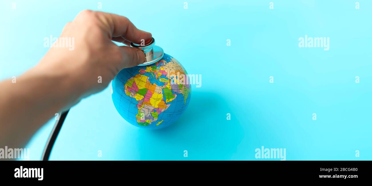 Doctor hand with stethoscope listening to small world ball on pastel blue background with copy space for text. Caring for planet Earth. Stock Photo