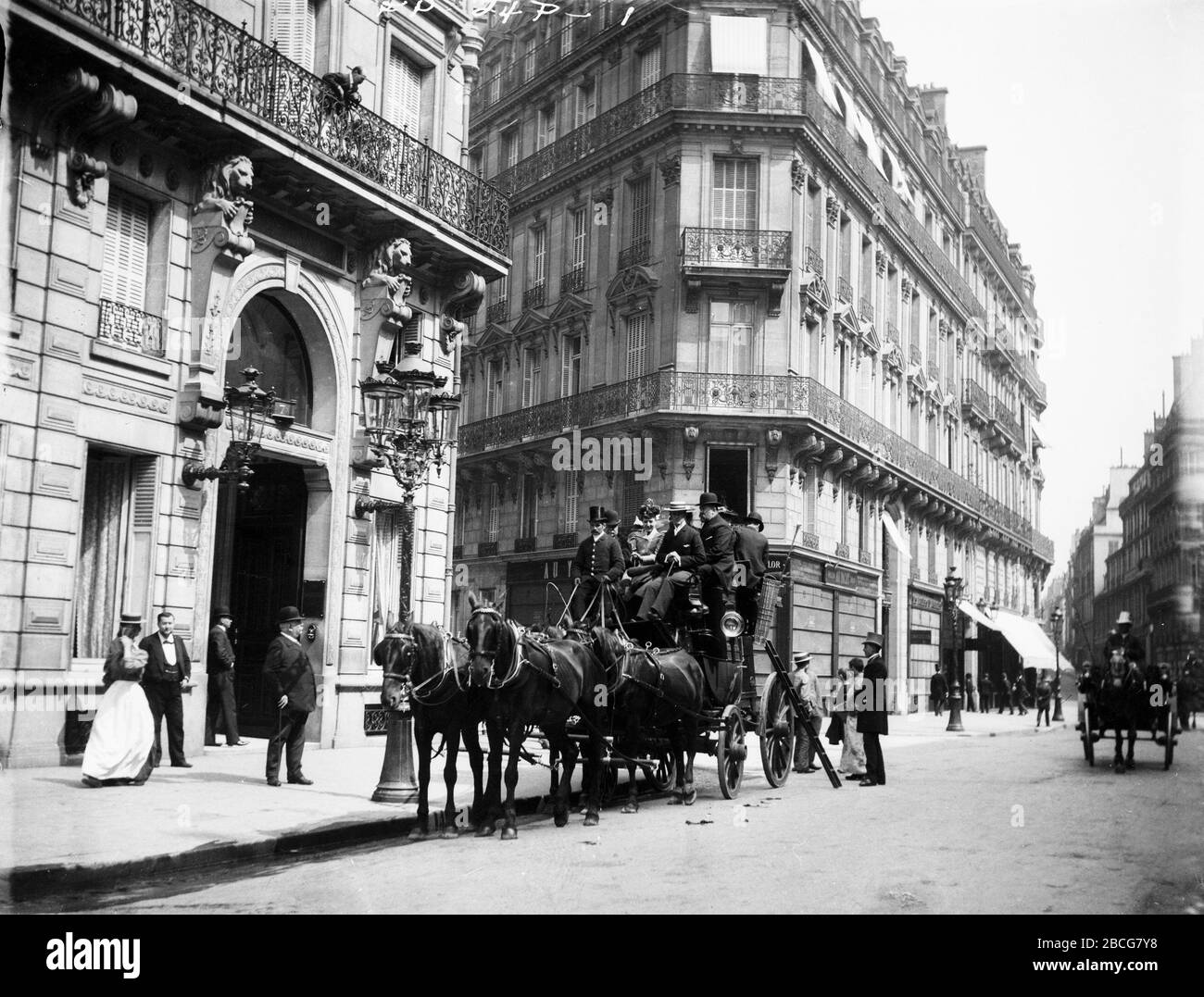 Passengers sit aboard a horse-drawn coach stopped outside the Normandy Hotel, Paris, France, 1895. (Photo by Burton Holmes) Stock Photo