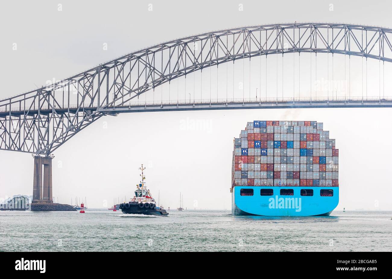 container vessel leaving the Panama Canal and passing the bridge of the Americas, the only road connection between north and south America Stock Photo