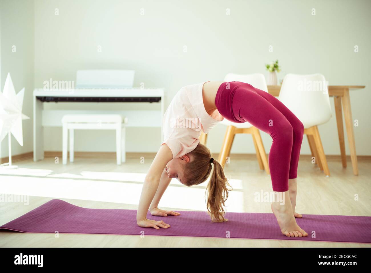 Pretty happy child girl having fun making yoga exercises at home during ...