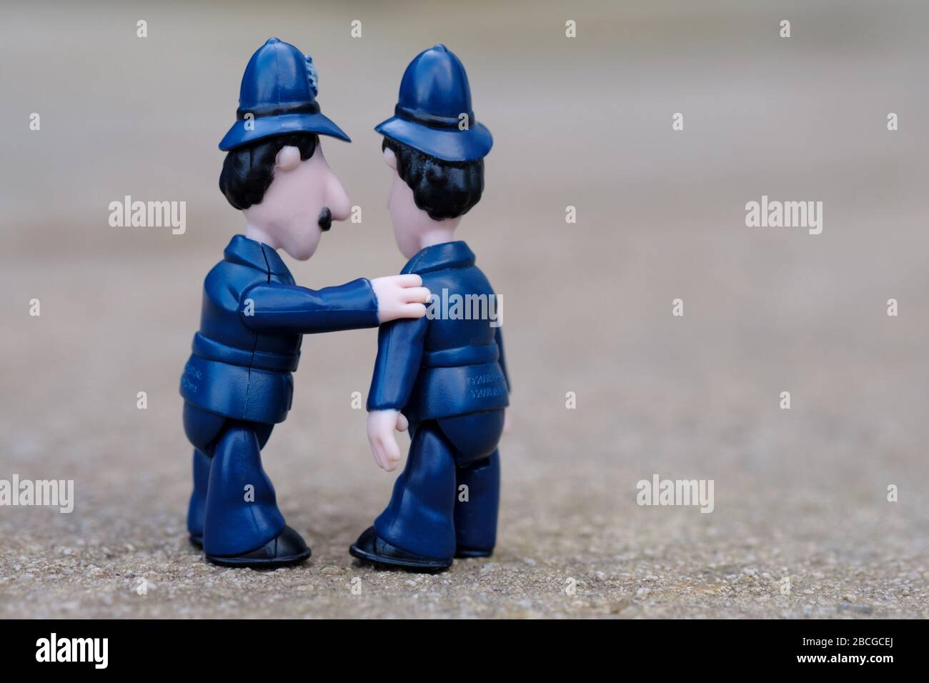 A comical shot of two toy English Policeman. One has his hand on the others shoulder and appears to be talking quietly to him Stock Photo