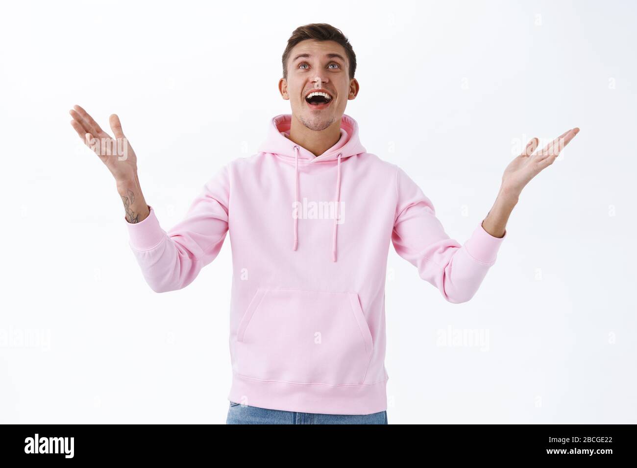 Relieved young happy man rejoicing over miracle happened, raising hands up at sky, thanking god for achieving his goal, wish came true, cant believe Stock Photo