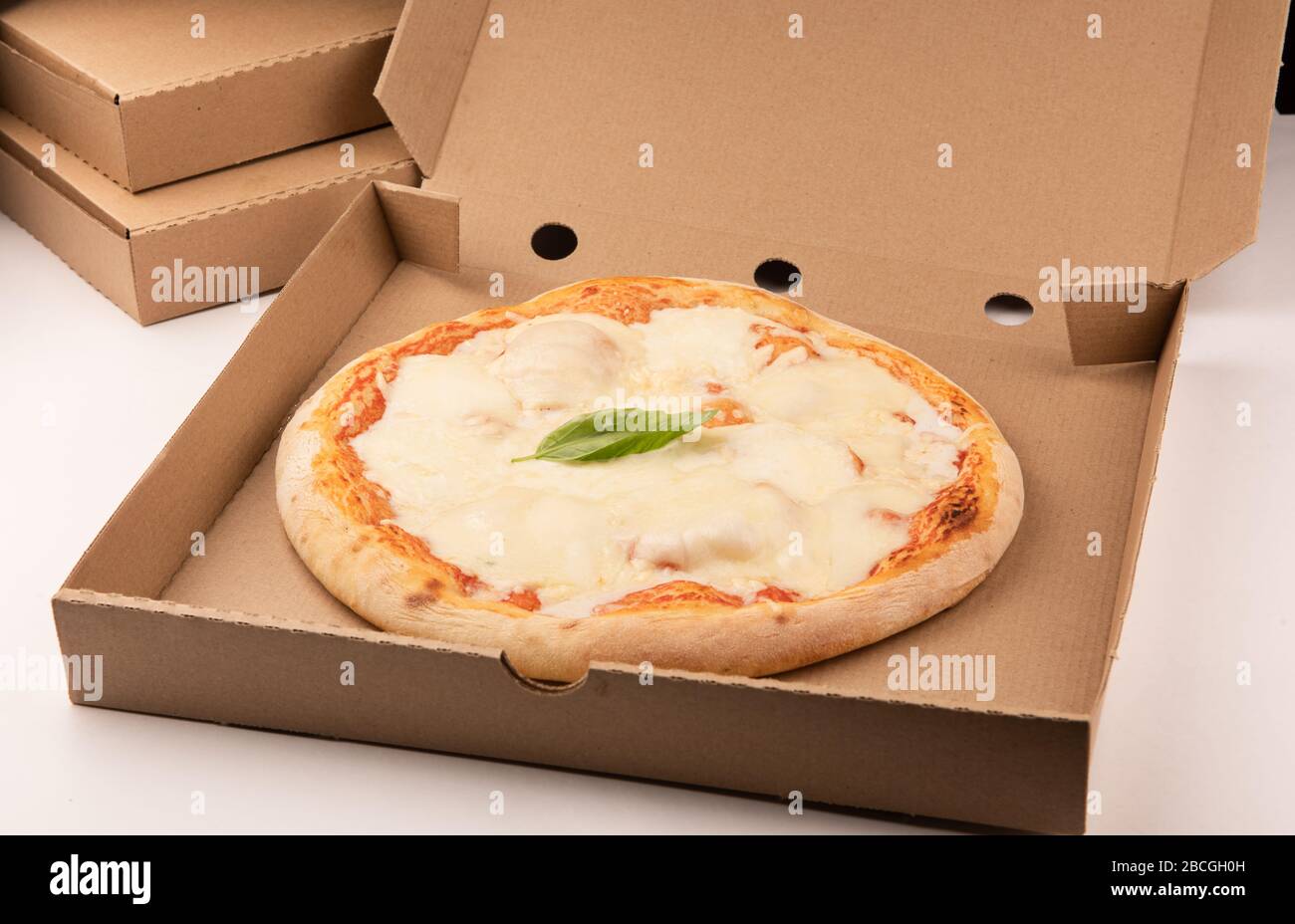 Pizza inside open box on tall stack of delivery boxes close up Stock Photo
