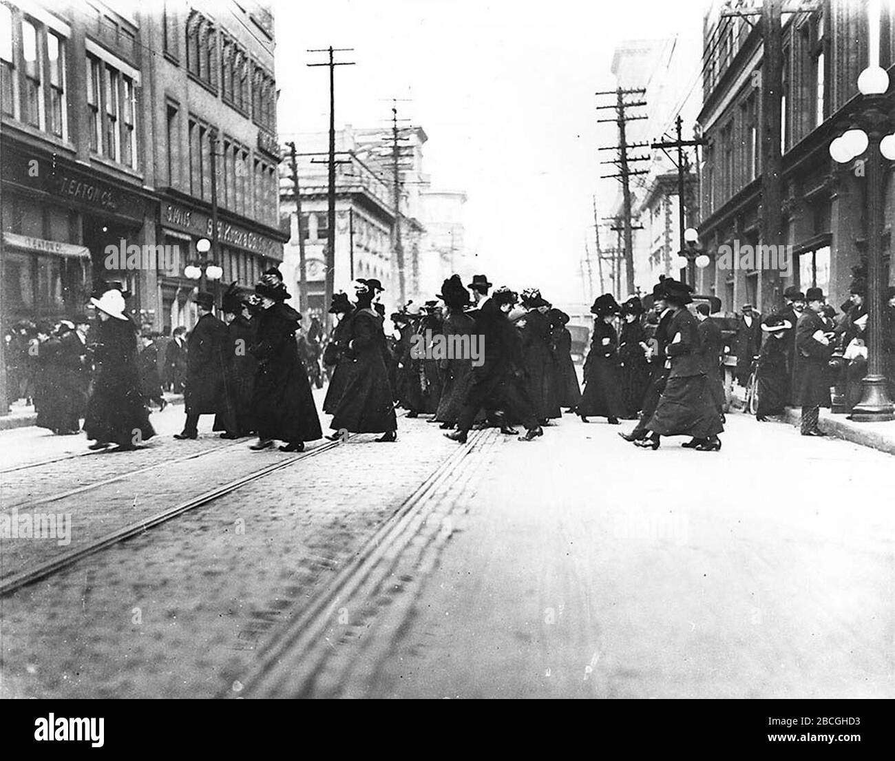 Queen Street West, looking east towards Yonge Street. Shoppers cross  between the Simpsons (right) and Eaton's (left) department stores on  opposite sides of the street. (Toronto, Canada); 1910; This image is  available