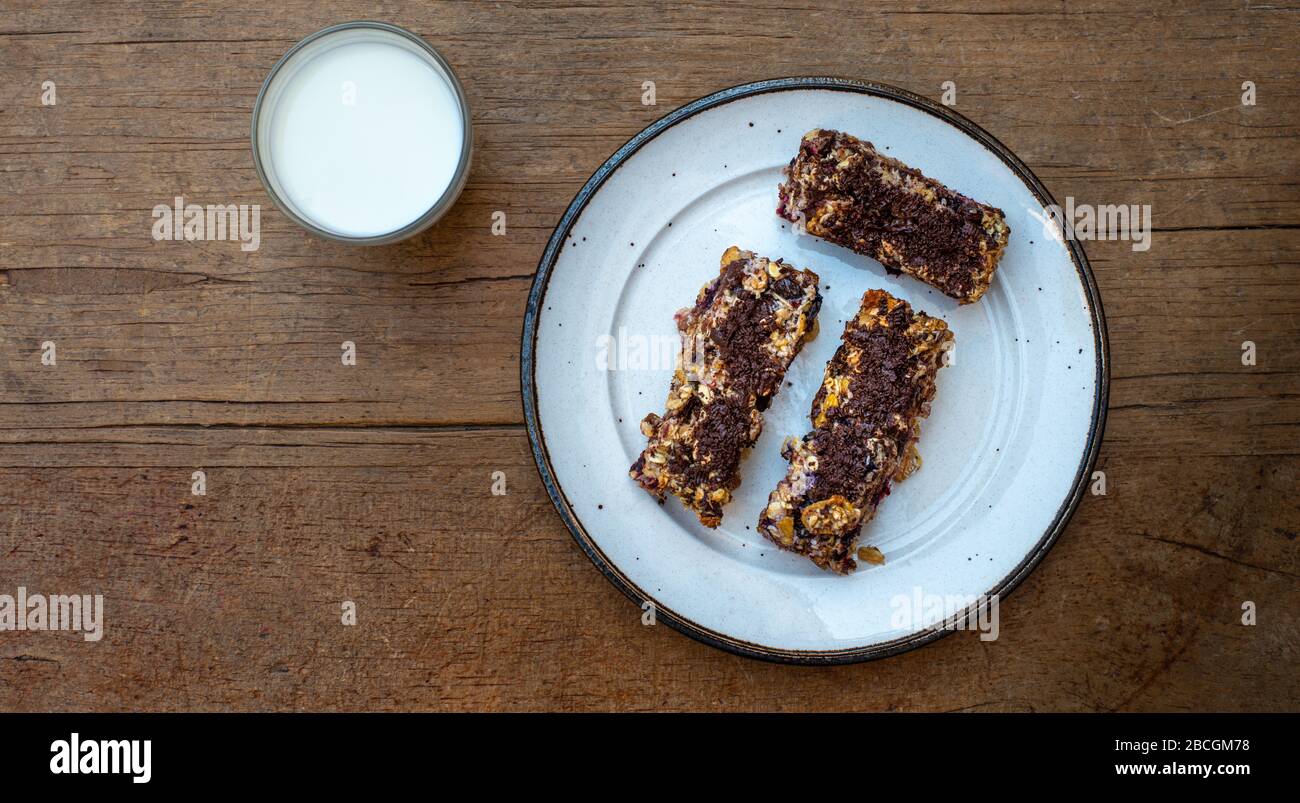 home made healthy cereal bars.in kitchen with glass of milk  honey pot ,& drizzler, Stuck at home. Stock Photo