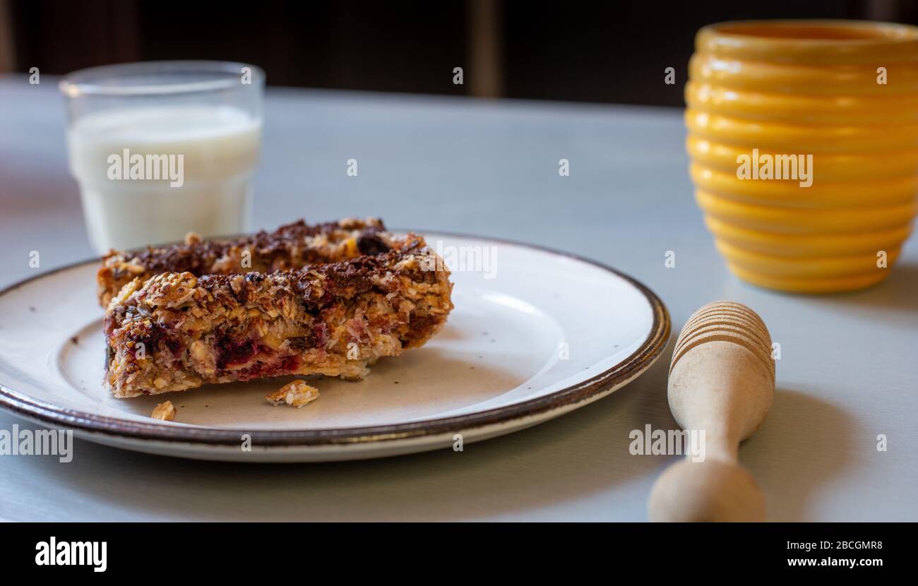 home made healthy cereal bars.in kitchen with glass of milk  honey pot ,& drizzler, Stock Photo