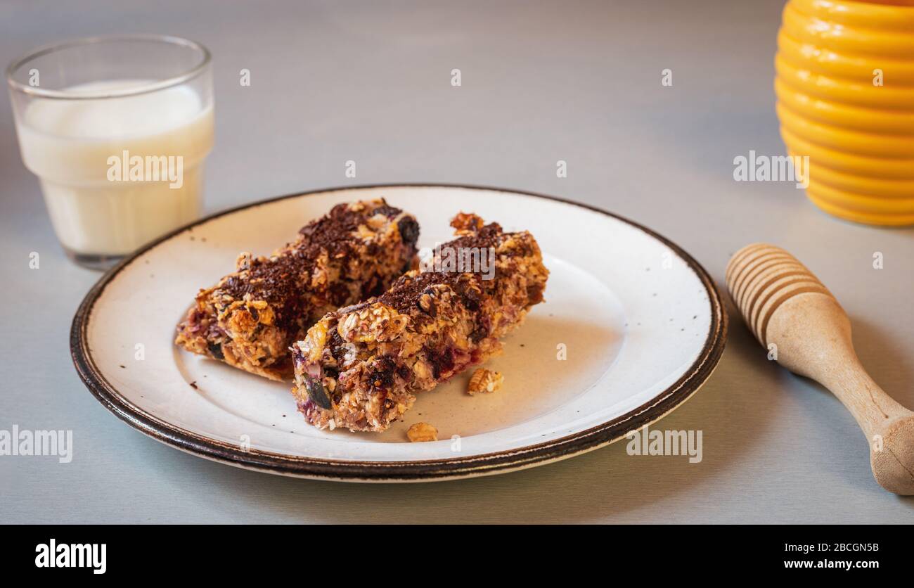 home made healthy cereal bars.in kitchen with glass of milk  honey pot ,& drizzler, Stock Photo