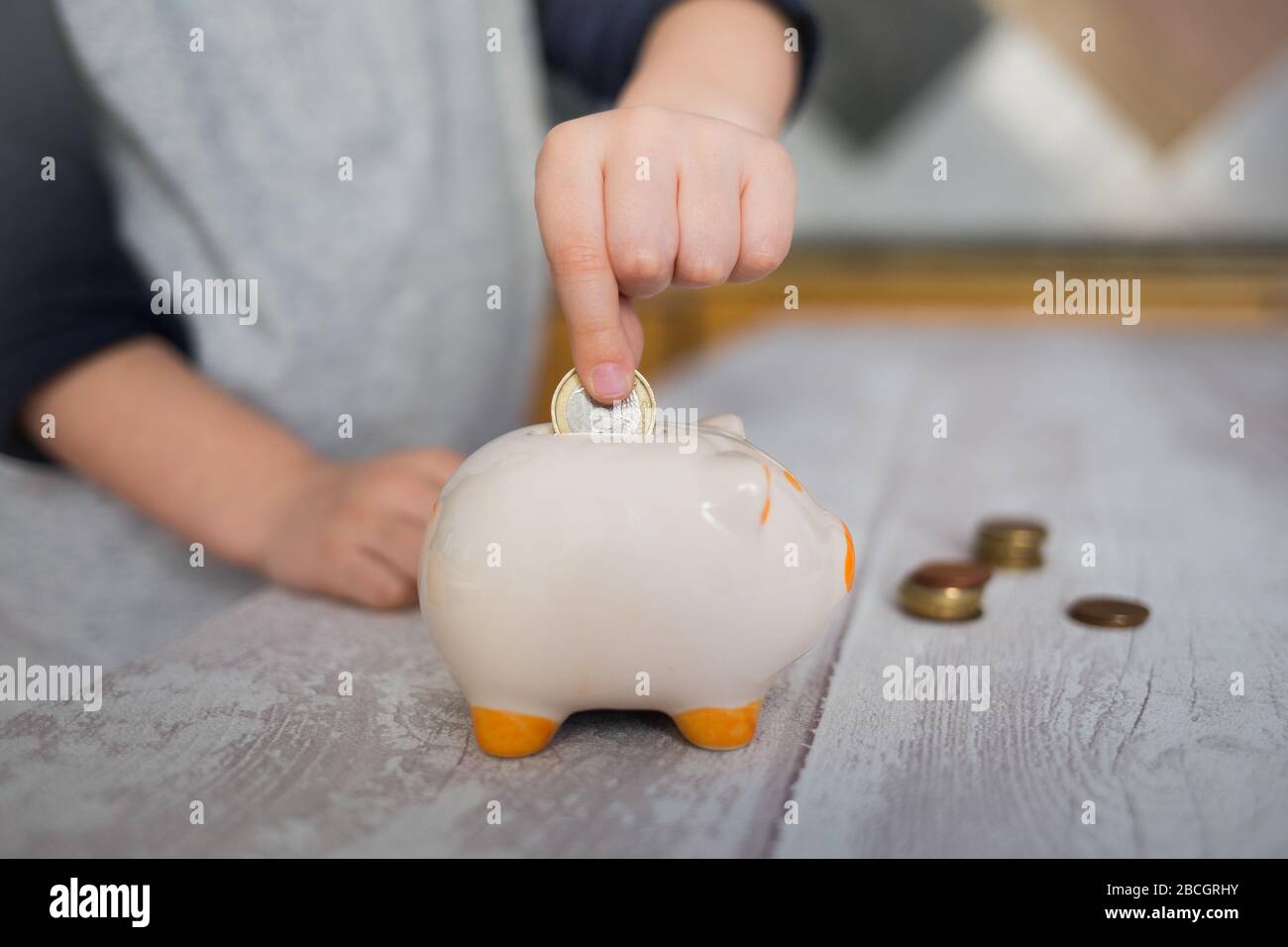 Hand of a child putting a coin into the piggy bank Stock Photo - Alamy