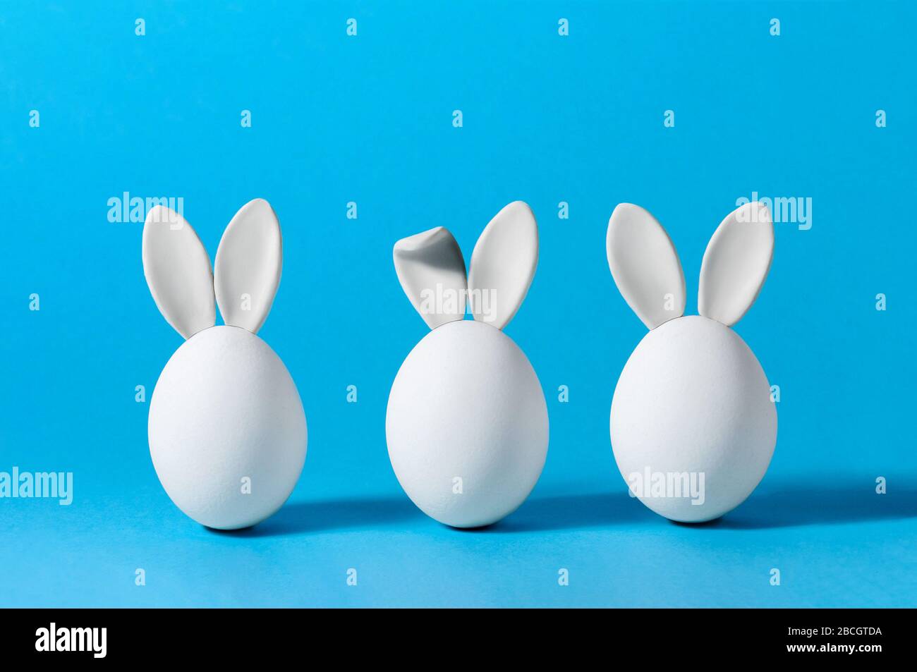 Easter Eggs with Bunny Ears on Blue Background. Creative Greeting Card. Minimalism Concept. Copy Space For Your Text Stock Photo