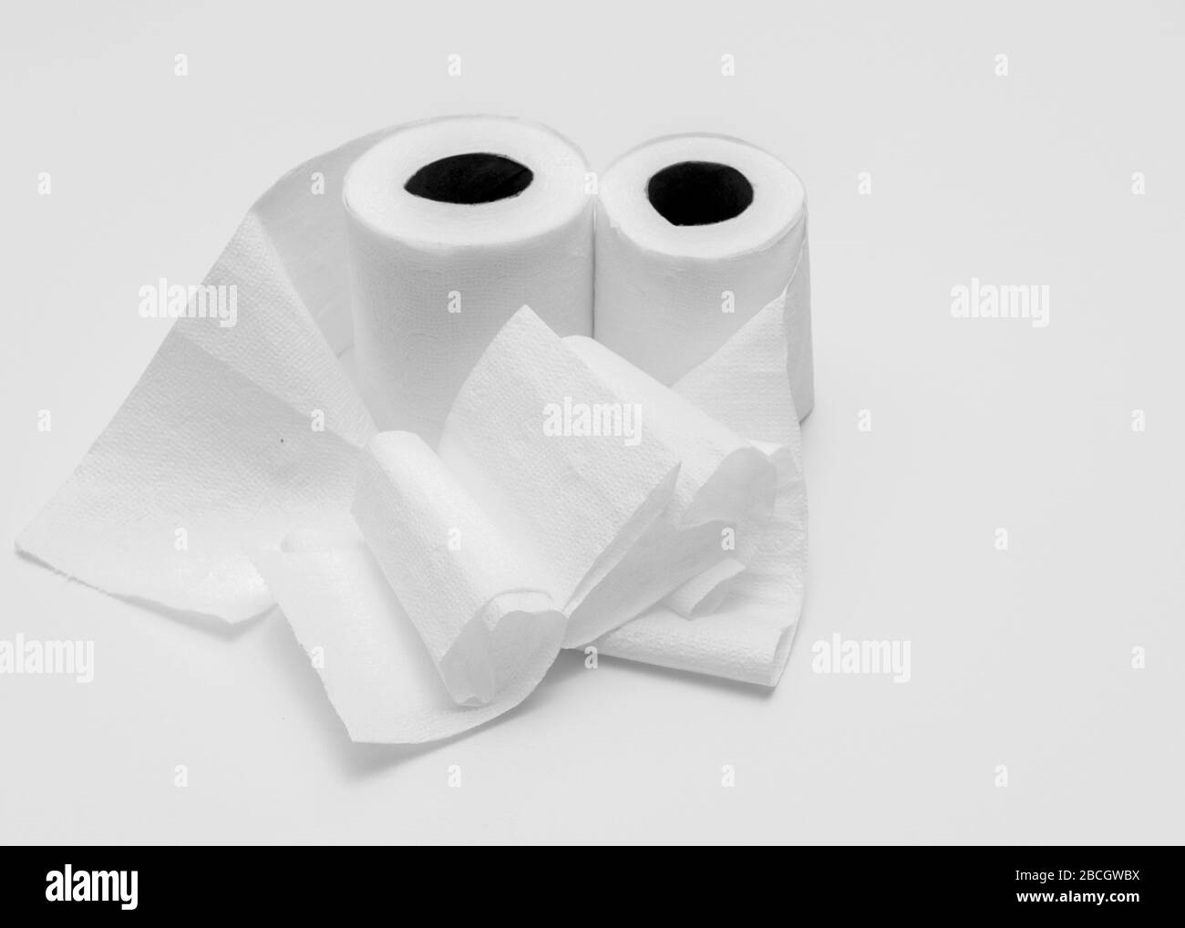 Two rolls of white toilet paper on white background, partly unrolled