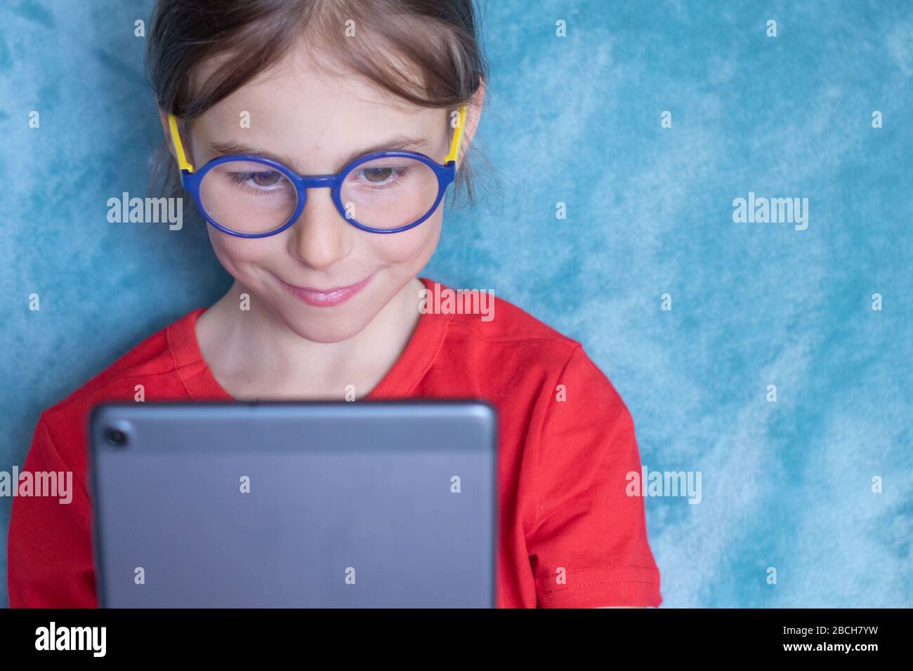 Child elementary school girl in glasses with tablet computer on