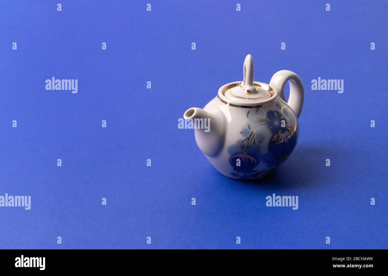 Tea in old fashioned kettle on classic blue background Stock Photo - Alamy