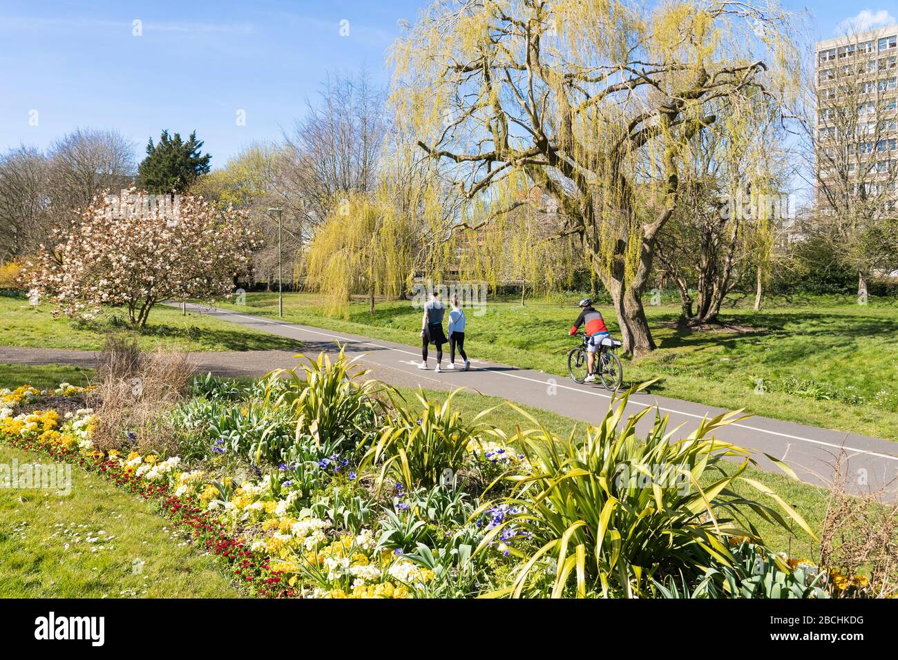 People in Eastrop Park enjoying spring sunshine and keeping safe social distancing during the Coronavirus pandemic, 4th April 2020, Basingstoke, UK Stock Photo