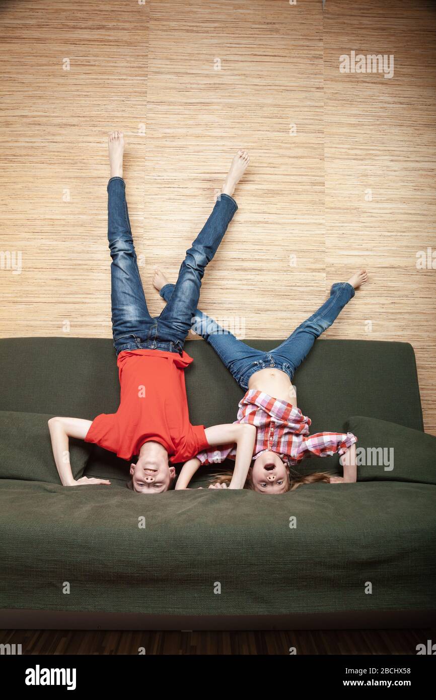 Siblings climbing the walls going mad stuck at home during isolation. Quarantine and lockdown protective measures against spreading of coronavirus pan Stock Photo