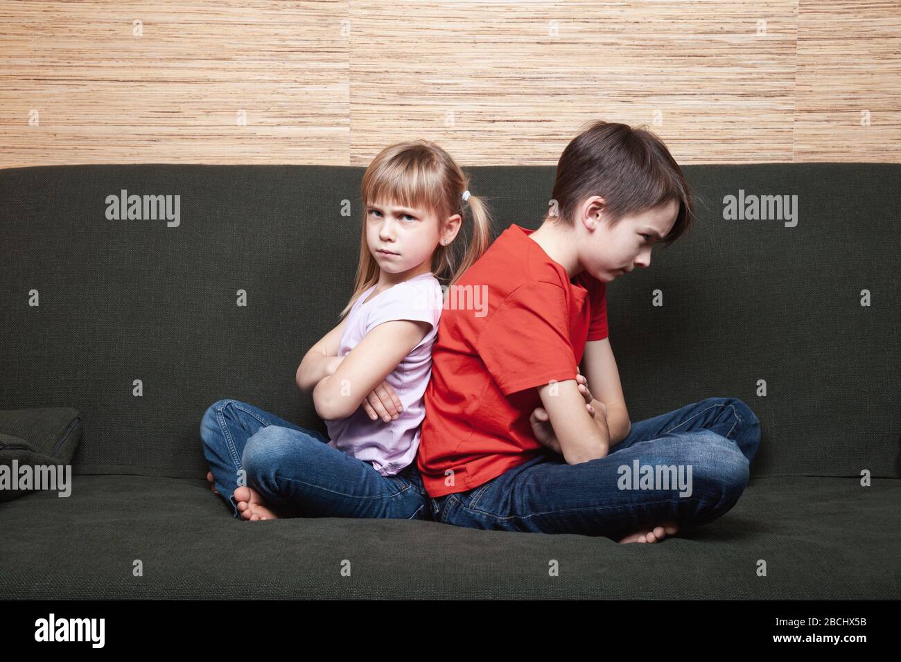 Frustrated siblings sittng on sofa stuck at home during isolation