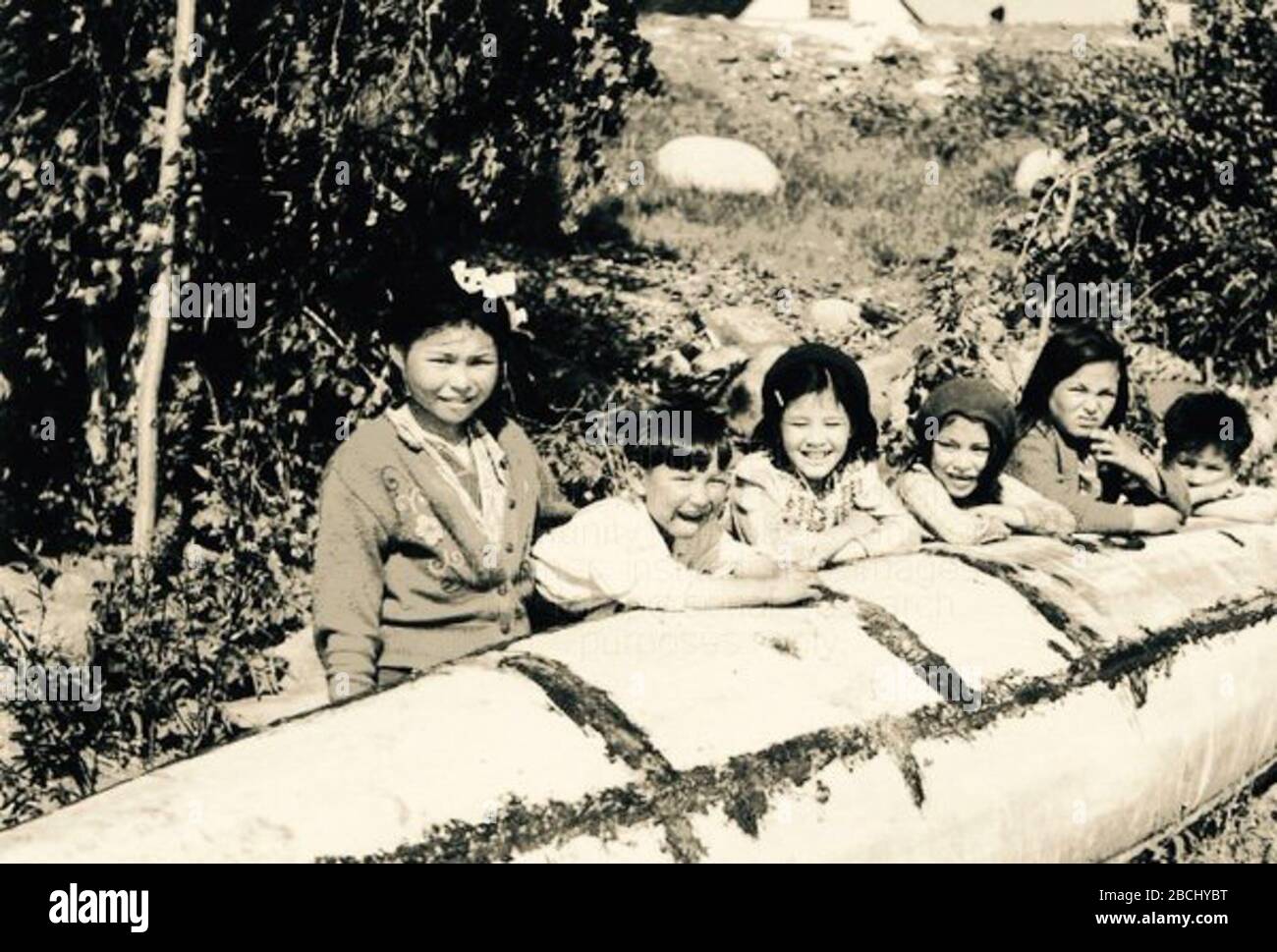 'English: 'Kids by canoe'  (Dene)  La Loche, Sask 1943; 1943; https://twitter.com/paulseesequa/status/703675760704299008; Sask History Room; ' Stock Photo