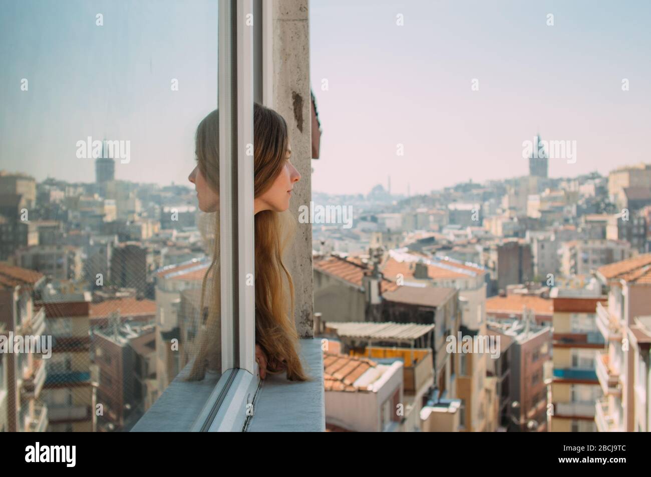 Beautiful girl with blond hair looking from the window, old district of Istanbul, Turkey Stock Photo