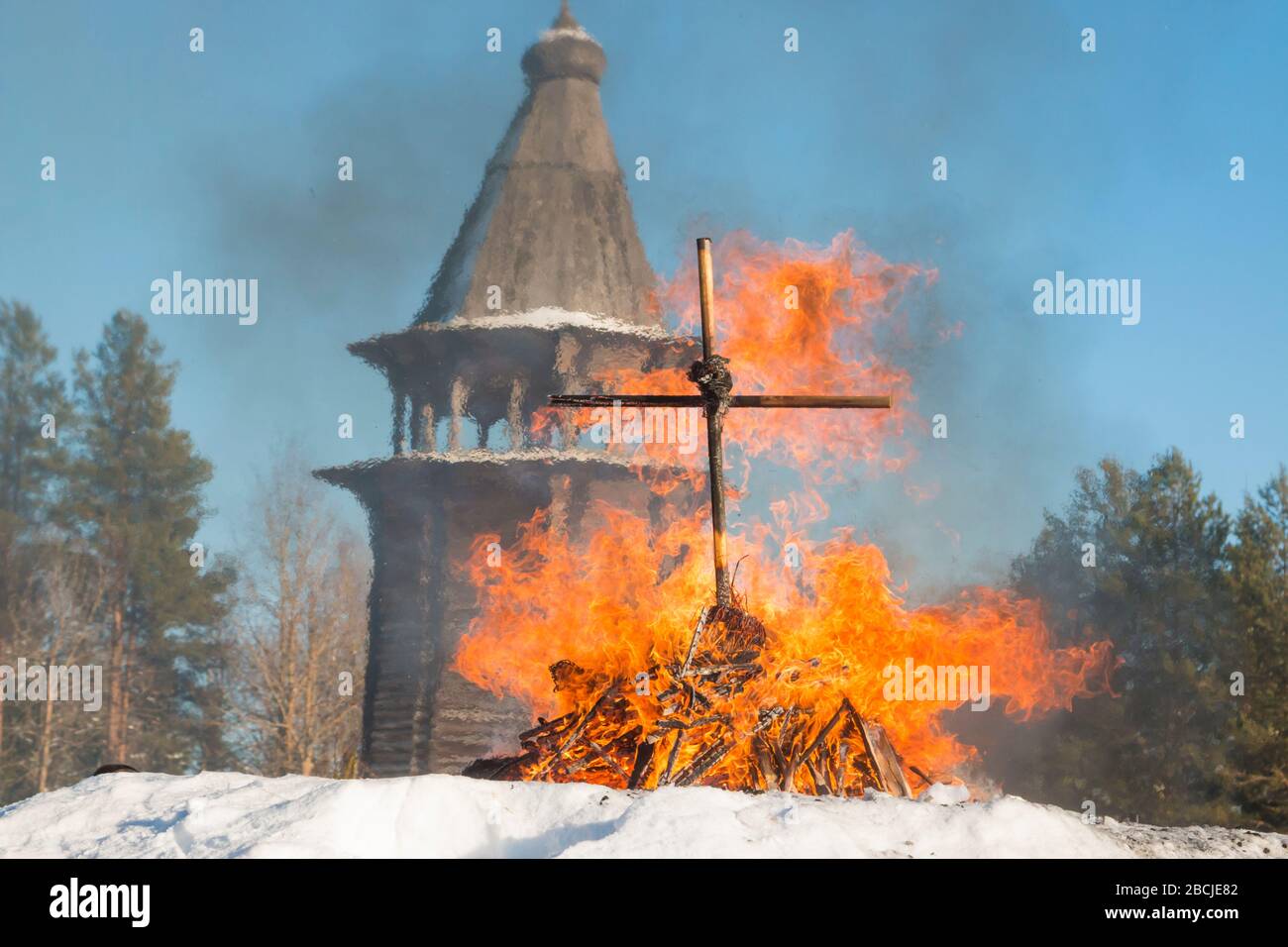 Burning cross on the background of a wooden bell tower Stock Photo