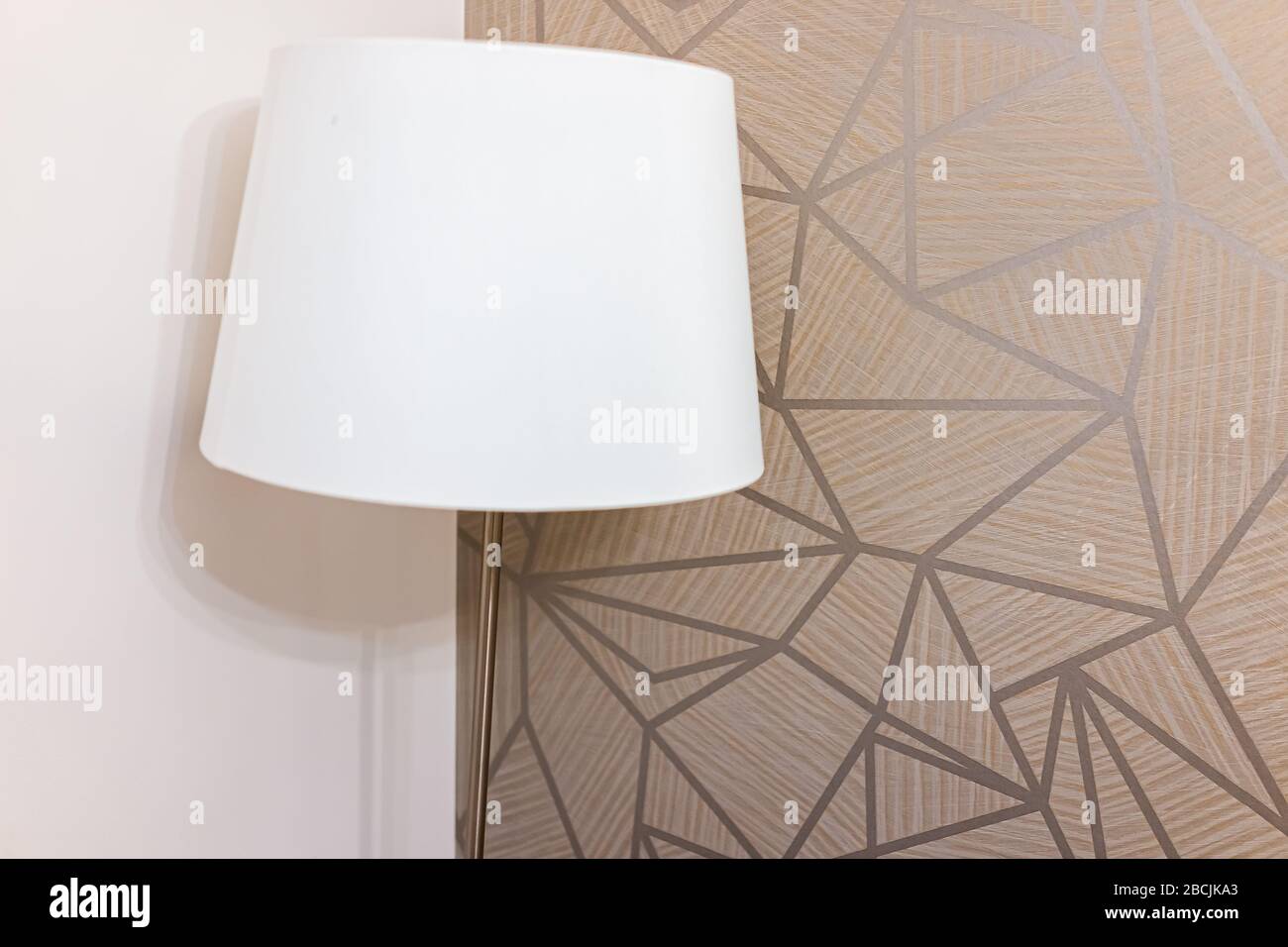 Closeup of white lamp light in bedroom or living room decoration with geometric patterns in corner wall of house or apartment hotel Stock Photo