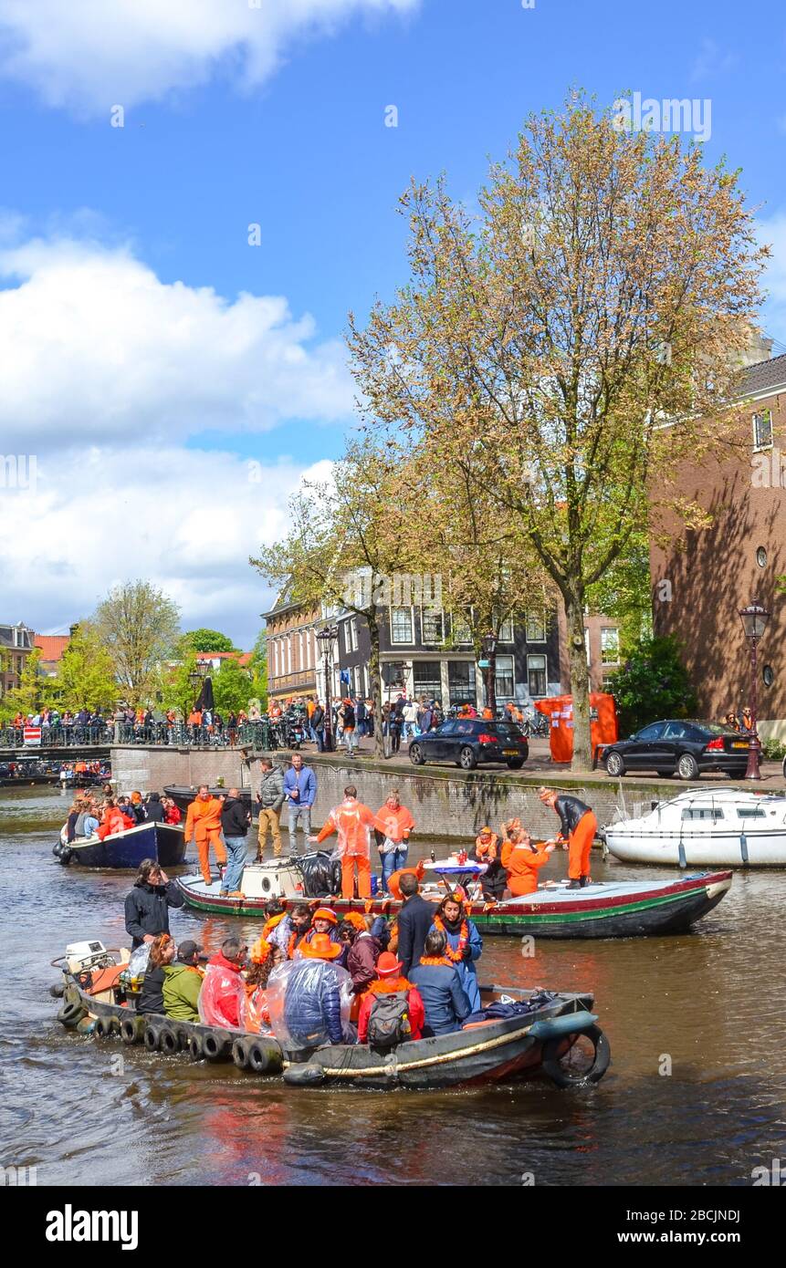 Amsterdam, Netherlands - April 27, 2019: People on party boats dressed in national orange color while celebrating the Kings day, Koningsdag, the birthday of the Dutch King Willem-Alexander. Stock Photo