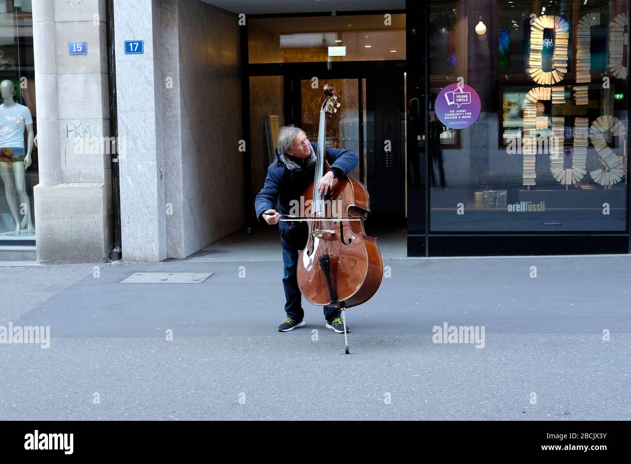 Due to coronavirus lockdown,the normally crowded Freiestrasse in Basel is empty, except for this busker. Stock Photo