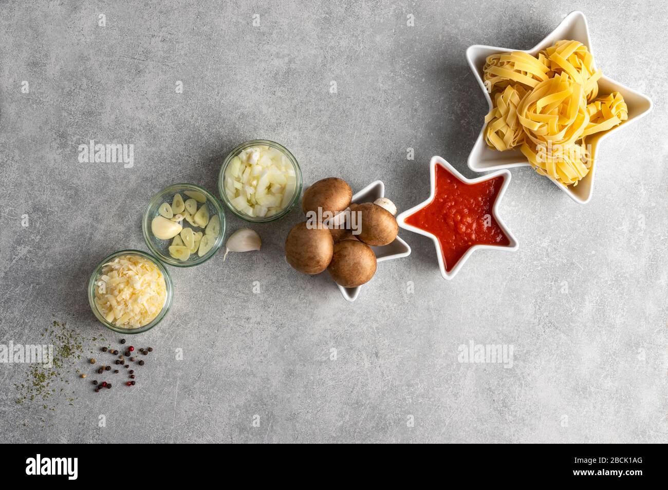 Dried pasta, mushrooms and vegetables on stone grrey background table top view, with copy space. Concept star composition tagliatelle and vegan bologn Stock Photo