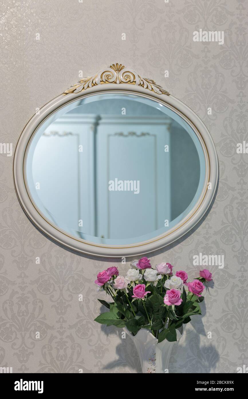 Round mirror on the wall and flowers multicolored installation closeup