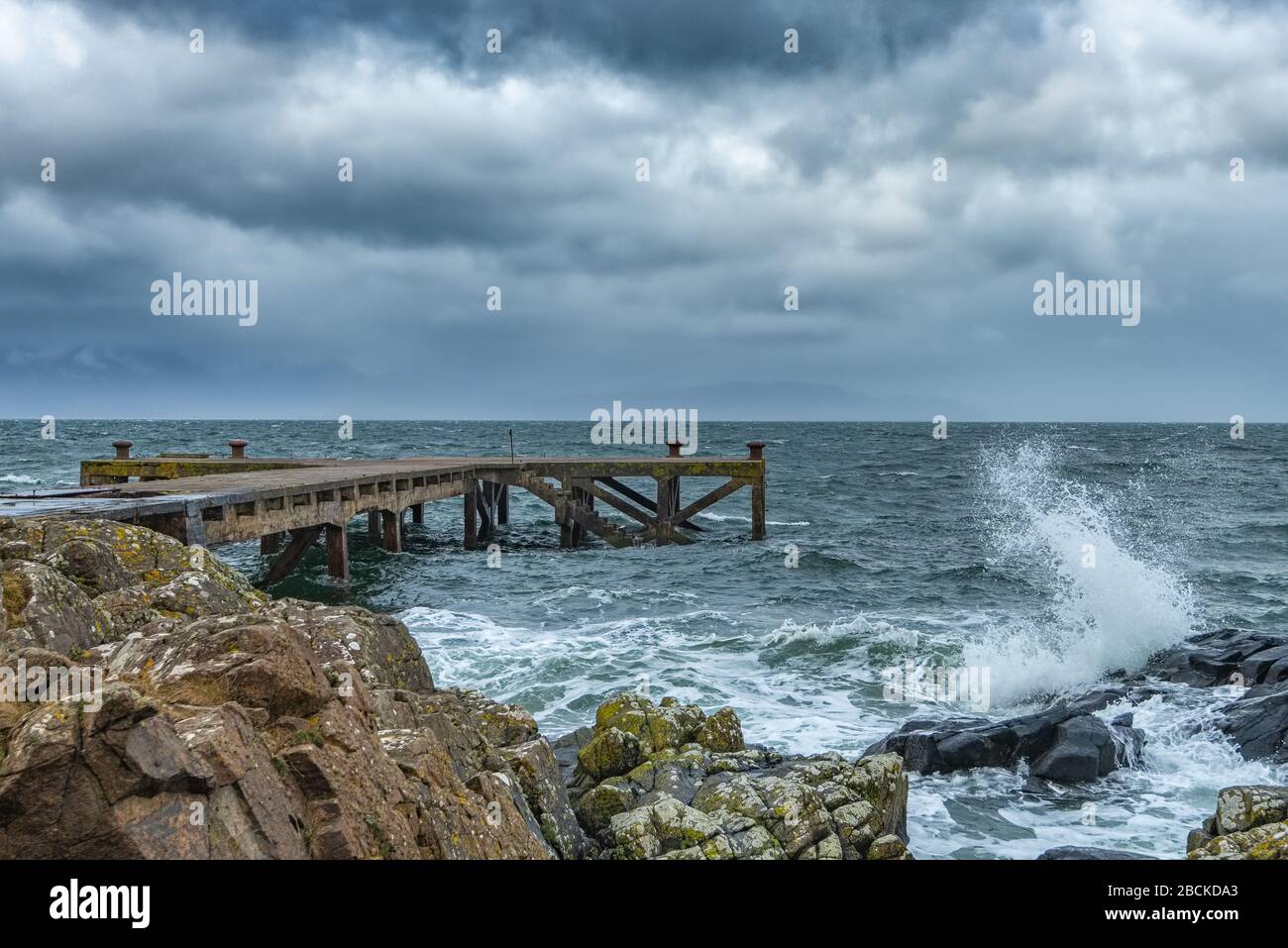 Looking over the rocky harbour  to the old jetty at Portencross in Seamill West Kilbride on a stormy March. Stock Photo