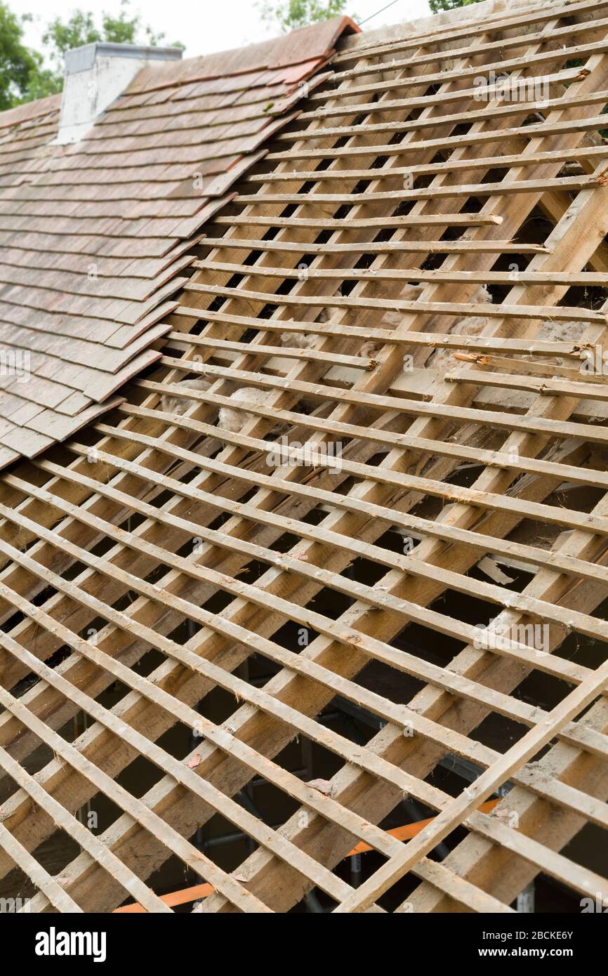 Replacing old tiles reveals failed spreading roof with broken rafters on a house in UK Stock Photo