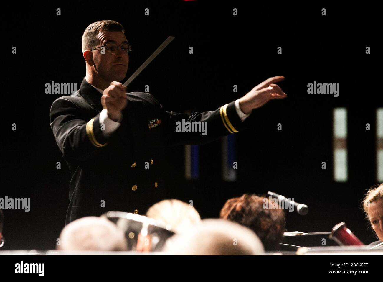 '131022-N-HG258-004 ASHBURN, VA (October 22, 2013) Lt. j.g. Bruce Mansfield, associate conductor with the United States Navy Band, directs the band during a daytime concert at Stonebridge H.S. in Ashburn, Va,. as part of it's Music in the Schools program. Music in the Schools is designed to supplement music education curricula and build bridges between the Navy and younger generations. (U.S. Navy Photo by MUC Stephen Hassay/Released); 23 October 2013, 10:50; Navy Band Music in the Schools at Stonebridge H.S. in Ashburn, Va.; United States Navy Band from Washington, D.C., USA; ' Stock Photo