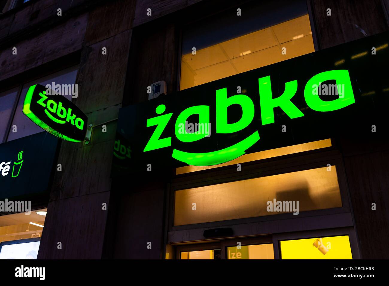 Warsaw, Poland - January 22, 2019: Illuminated sign closeup for Zabka green grocery supermarket convenience store on street in downtown center at nigh Stock Photo