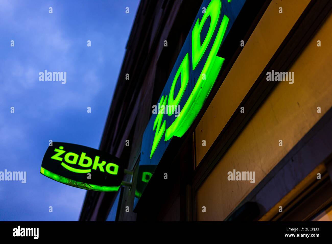 Warsaw, Poland - January 22, 2019: Sign closeup for Zabka green grocery supermarket convenience store on street in downtown center at night with blue Stock Photo