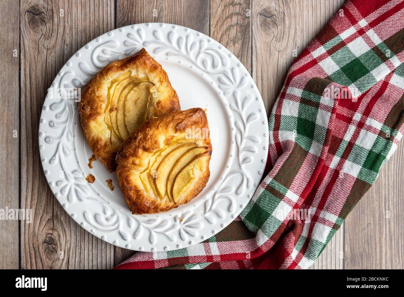 Fresh individual apple tarts on a white plate, red, green, and white cloth napkin, wood background Stock Photo