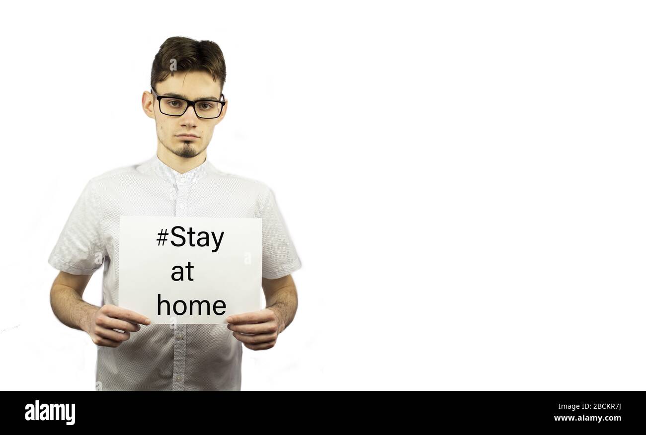 guy is holding white paper with the text - stay home. Covid-19. Stay at home. Self-isolation. Quarantine Stock Photo