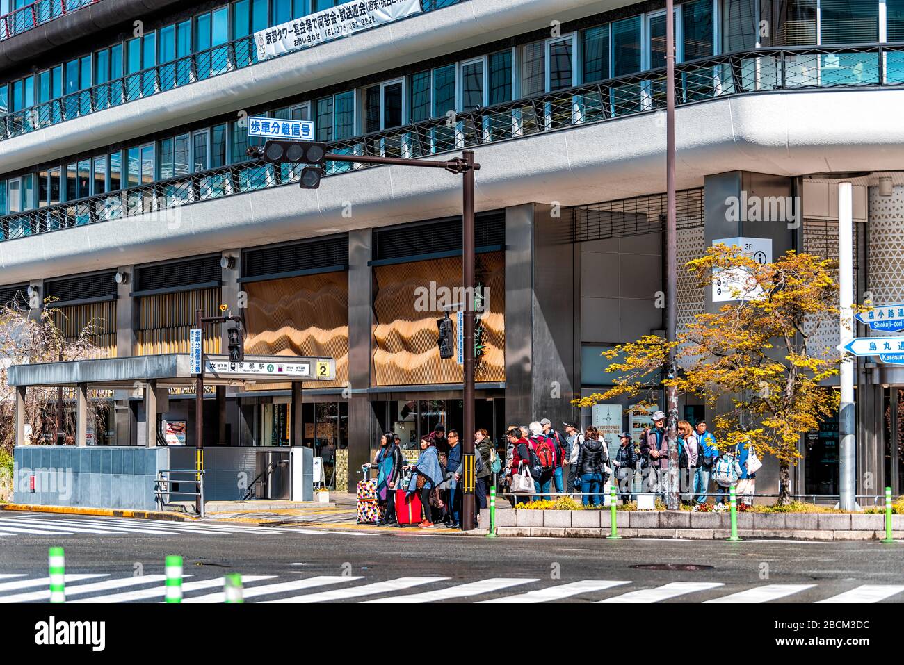 Kyoto, Japan - April 10, 2019: Street sidewalk crosswalk with many people tourists with luggage waiting to cross road pavement to station building dur Stock Photo