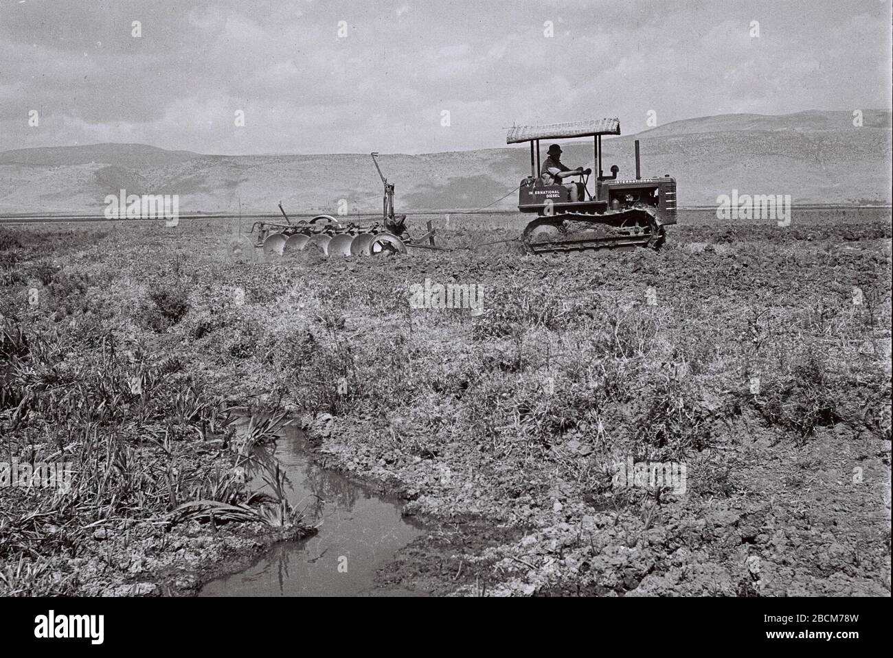 English The First Tractor Of Kibbutz Amir Ploughing The Land In The Hule Swamps O Ss O I E C I U C U Ss O E I U O U E I I O I C E Ss Ss I I U C Ss E U Ss I O I U I