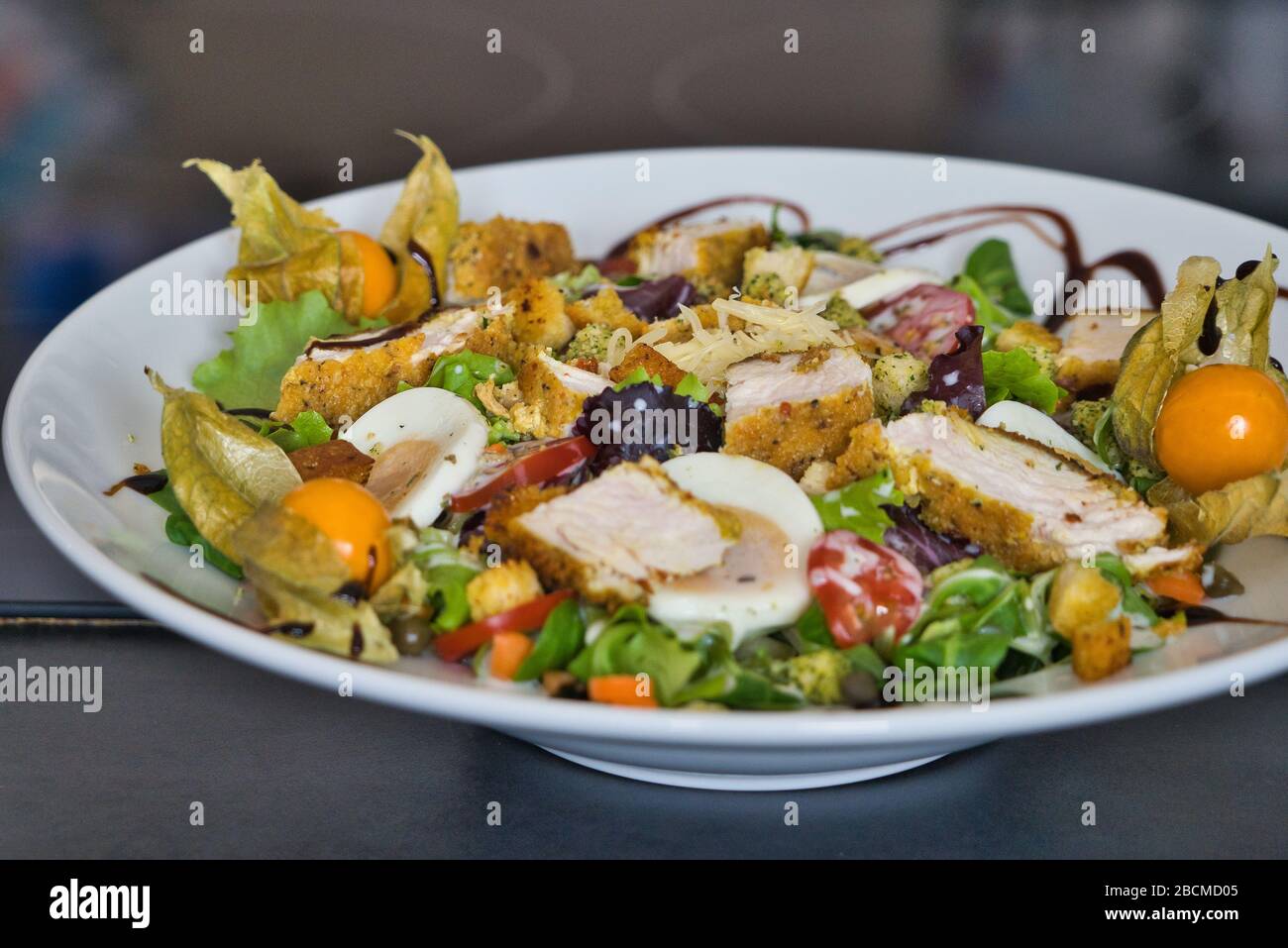 Mixed organic salad plate with chicken strips, tomatoes, eggs, bell pepper, field salad, balsamic vinegar and croutons, product image Stock Photo