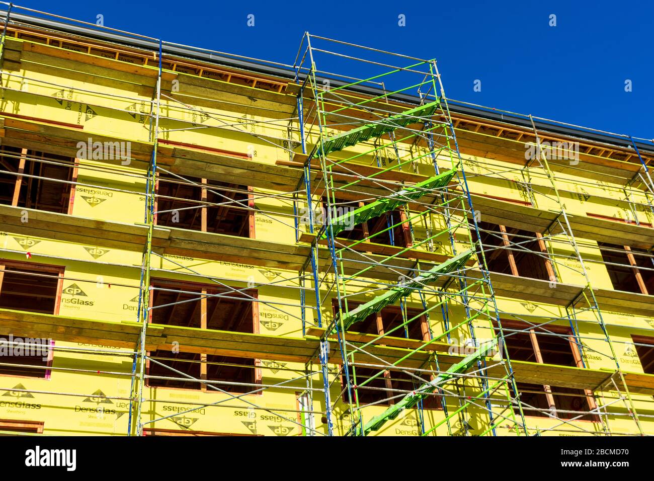 Scaffolding access stairs at new multifamily residential building facade protected by fiberglass mat gypsum sheathing during construction - Santa Jose Stock Photo